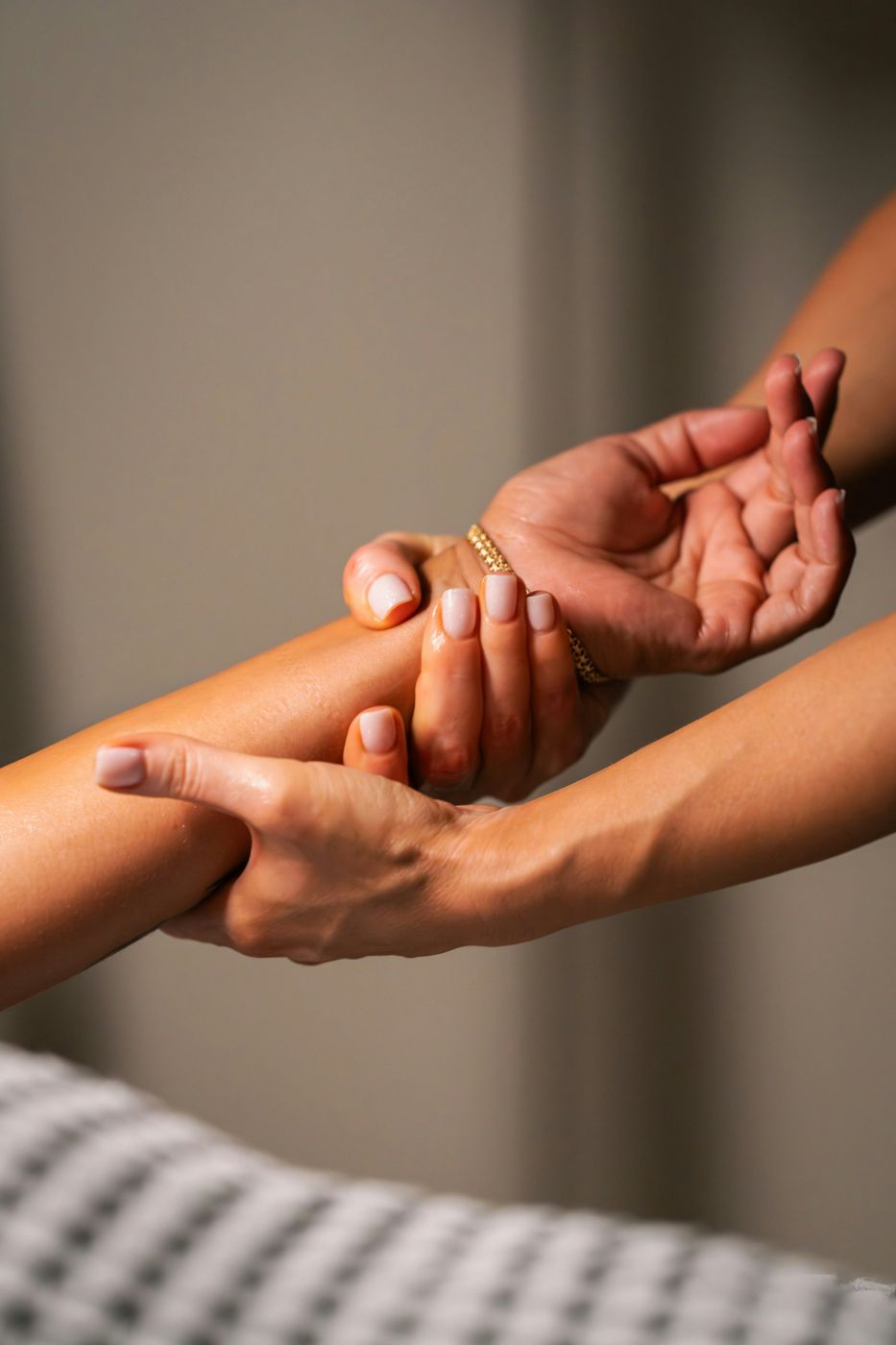 A practitioner's hands gently massaging a client's forearm and wrist